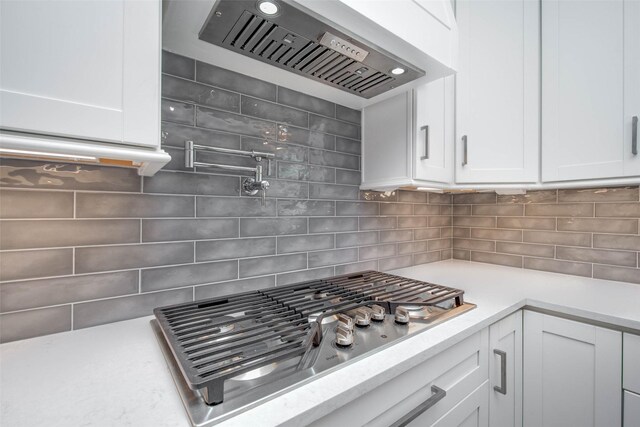 7710 Meadowvale Dr, Houston, TX 77063 - kitchen featuring extractor fan, stainless steel gas cooktop, tasteful backsplash, light countertops, and white cabinetry