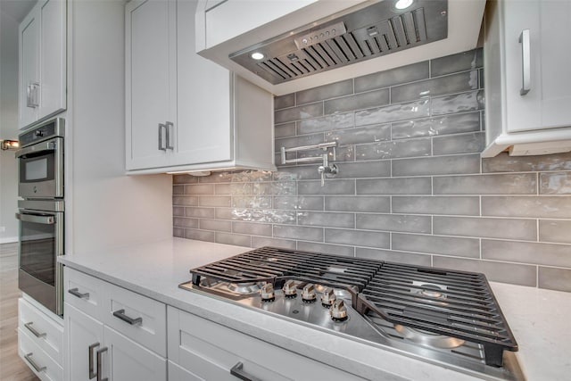 7710 Meadowvale Dr, Houston, TX 77063 - kitchen with stainless steel appliances, custom exhaust hood, white cabinetry, and backsplash