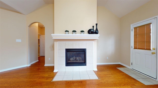 19943 Silver Rock Dr, Katy, TX 77449 - unfurnished living room with lofted ceiling, wood finished floors, arched walkways, and a fireplace