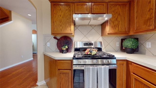 19943 Silver Rock Dr, Katy, TX 77449 - kitchen featuring stainless steel range with gas stovetop, extractor fan, arched walkways, and light countertops