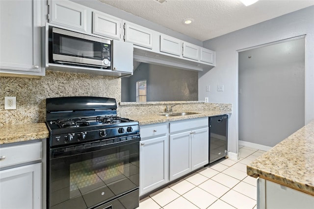 20062 S Pecos Valley Trl, Katy, TX 77449 - kitchen with black gas range, stainless steel microwave, dishwasher, light tile patterned floors, and a textured ceiling