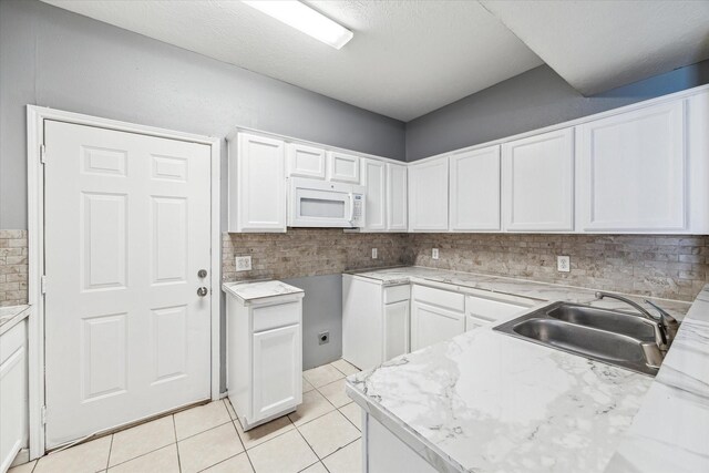 4340 Phlox St A/B, Unit A/B Houston, TX 77051 - kitchen featuring white microwave, tasteful backsplash, white cabinetry, light countertops, and light tile patterned flooring