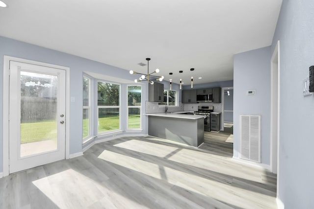 4211 Royal Manor Dr, Pasadena, TX 77505 - kitchen featuring appliances with stainless steel finishes, light wood-style floors, a chandelier, light countertops, and decorative backsplash