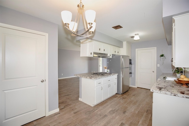 13329 24th St, Santa Fe, TX 77510 - kitchen featuring under cabinet range hood, stainless steel appliances, a chandelier, and white cabinetry
