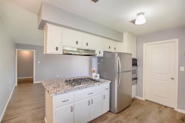 13329 24th St, Santa Fe, TX 77510 - kitchen featuring stainless steel appliances, under cabinet range hood, light wood-style flooring, white cabinetry, and a warming drawer
