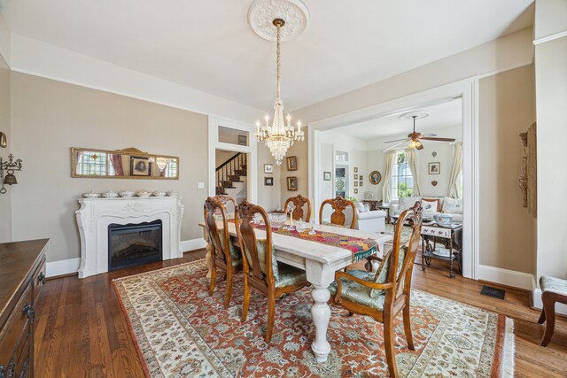 607 11th St, Galveston, TX 77550 - dining room featuring a chandelier, dark wood-style floors, stairway, a fireplace, and ceiling fan