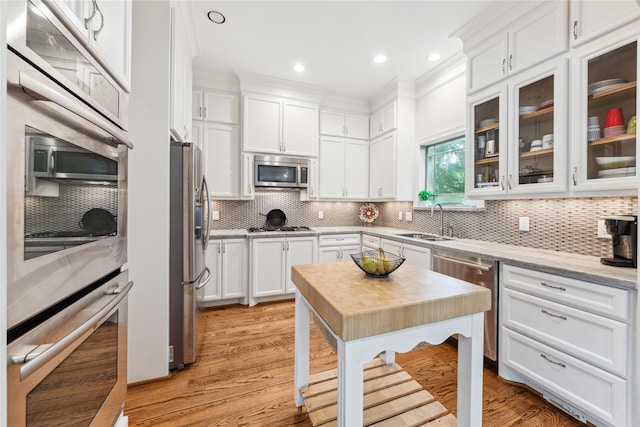 234 Knox St, Houston, TX 77007 - kitchen with appliances with stainless steel finishes, white cabinets, backsplash, light wood finished floors, and recessed lighting