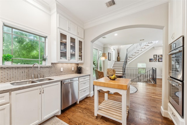234 Knox St, Houston, TX 77007 - kitchen with stainless steel appliances, ornamental molding, white cabinetry, glass insert cabinets, and tasteful backsplash