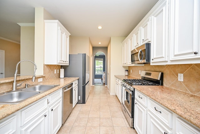 28503 Cece Glen Ct, Spring, TX 77386 - kitchen featuring stainless steel appliances, arched walkways, white cabinetry, tasteful backsplash, and light tile patterned floors