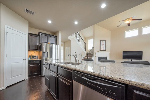 4310 Tilbury Trl, Richmond, TX 77407 - kitchen featuring appliances with stainless steel finishes, a ceiling fan, light stone counters, open floor plan, and dark wood-style floors