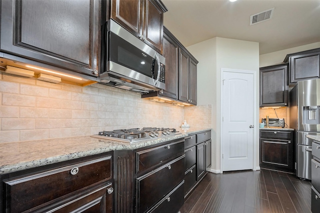 4310 Tilbury Trl, Richmond, TX 77407 - kitchen featuring stainless steel appliances, dark brown cabinetry, light stone counters, dark wood finished floors, and tasteful backsplash