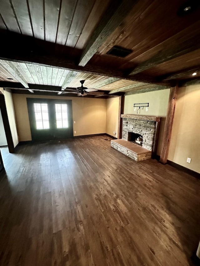 4842 Green Trail Dr, Houston, TX 77084 - unfurnished living room featuring dark wood-type flooring, a wooden ceiling with exposed beams, a stone fireplace, and ceiling fan