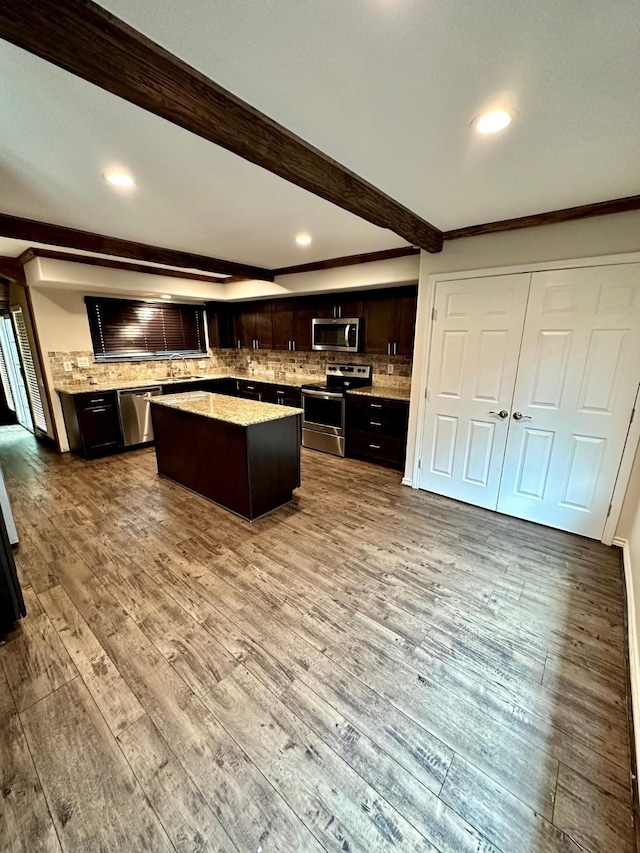 4842 Green Trail Dr, Houston, TX 77084 - kitchen featuring stainless steel appliances, a kitchen island, beam ceiling, dark brown cabinets, and decorative backsplash