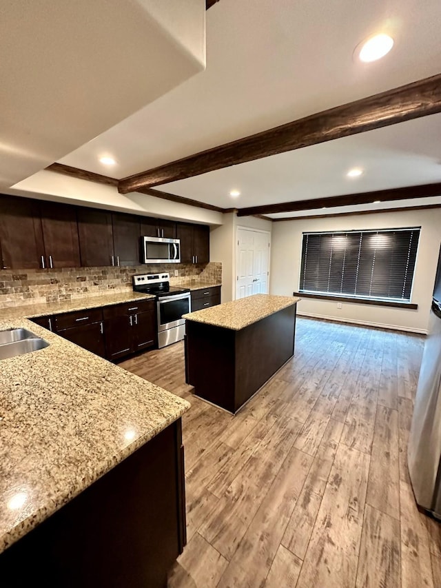 4842 Green Trail Dr, Houston, TX 77084 - kitchen featuring stainless steel appliances, a center island, dark brown cabinets, light wood-style flooring, and decorative backsplash