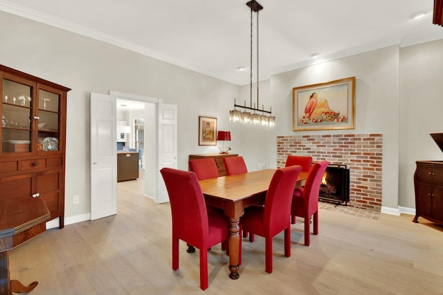 13718 Gainesway Dr, Cypress, TX 77429 - dining space featuring light wood-type flooring, crown molding, a brick fireplace, and recessed lighting