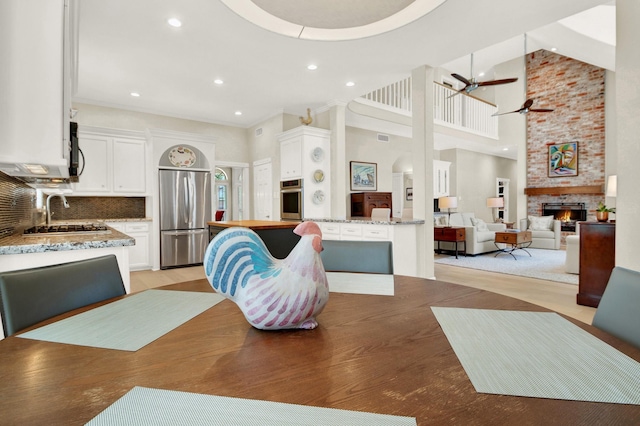13718 Gainesway Dr, Cypress, TX 77429 - dining space featuring a ceiling fan, a fireplace, recessed lighting, and a towering ceiling