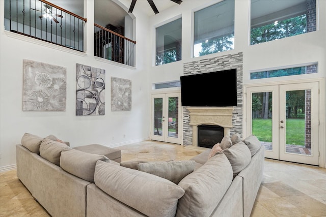 14610 Majestic Oaks, Magnolia, TX 77354 - living room featuring french doors, a high ceiling, plenty of natural light, a glass covered fireplace, and stone finish floors