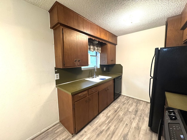 1722 Briar Ln, Wharton, TX 77488 - kitchen with a textured ceiling, light wood-style flooring, black appliances, dark countertops, and brown cabinets
