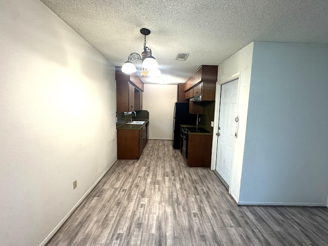 1722 Briar Ln, Wharton, TX 77488 - kitchen with wood finished floors, stove, a chandelier, a textured ceiling, and dark countertops