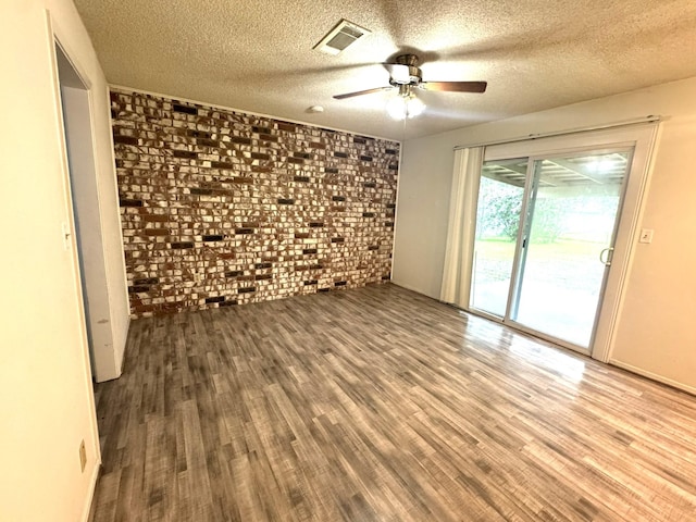 1722 Briar Ln, Wharton, TX 77488 - empty room with brick wall, wood finished floors, a ceiling fan, and a textured ceiling