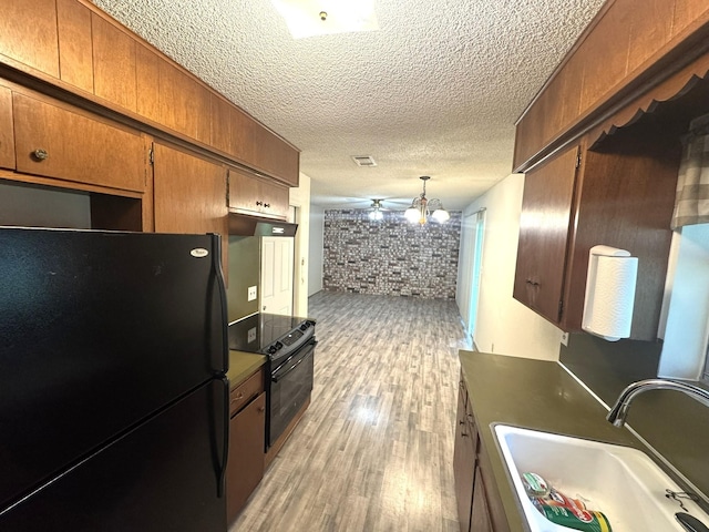 1722 Briar Ln, Wharton, TX 77488 - kitchen featuring black appliances, brick wall, light wood-style floors, a textured ceiling, and brown cabinetry