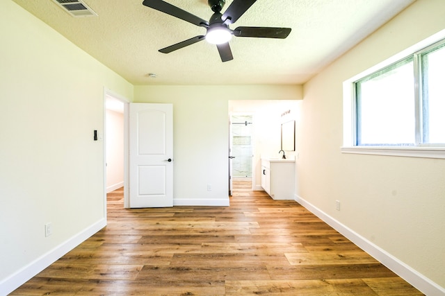 6303 Tamar Dr, Pasadena, TX 77503 - unfurnished bedroom featuring multiple windows, a textured ceiling, wood finished floors, connected bathroom, and ceiling fan