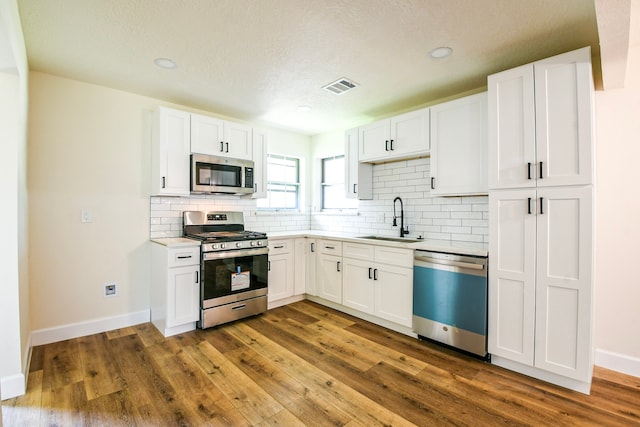 6303 Tamar Dr, Pasadena, TX 77503 - kitchen featuring stainless steel appliances, decorative backsplash, white cabinets, light countertops, and a textured ceiling