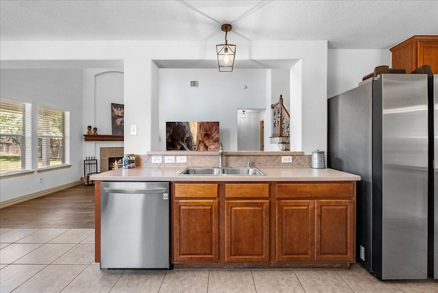 6907 Autumn Rain Ln, Spring, TX 77379 - kitchen with appliances with stainless steel finishes, light countertops, brown cabinetry, and a tile fireplace