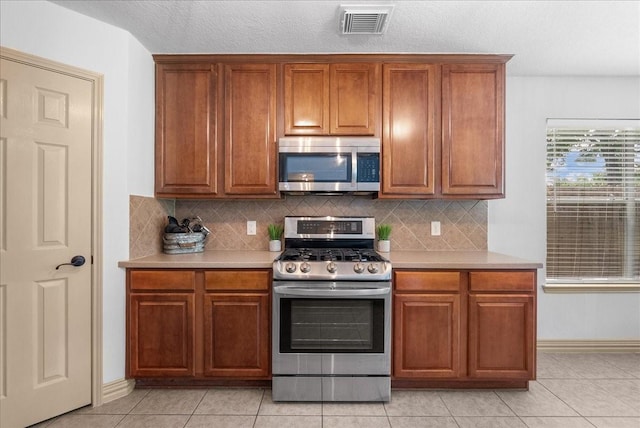 6907 Autumn Rain Ln, Spring, TX 77379 - kitchen featuring appliances with stainless steel finishes, light countertops, brown cabinetry, and decorative backsplash