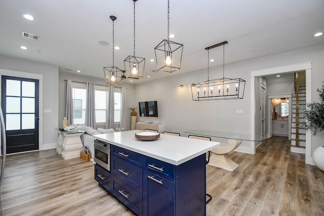 1315 Wycliffe Dr, Houston, TX 77043 - kitchen with blue cabinetry, a kitchen island, recessed lighting, light wood finished floors, and light countertops