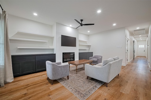 2015 Creston Dr, Houston, TX 77026 - living area with a glass covered fireplace, light wood finished floors, a ceiling fan, recessed lighting, and built in shelves