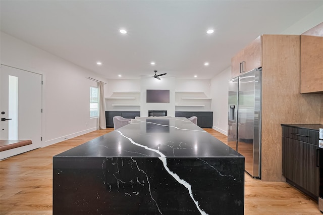 2015 Creston Dr, Houston, TX 77026 - kitchen with a fireplace, stainless steel refrigerator with ice dispenser, ceiling fan, a center island, and light wood finished floors