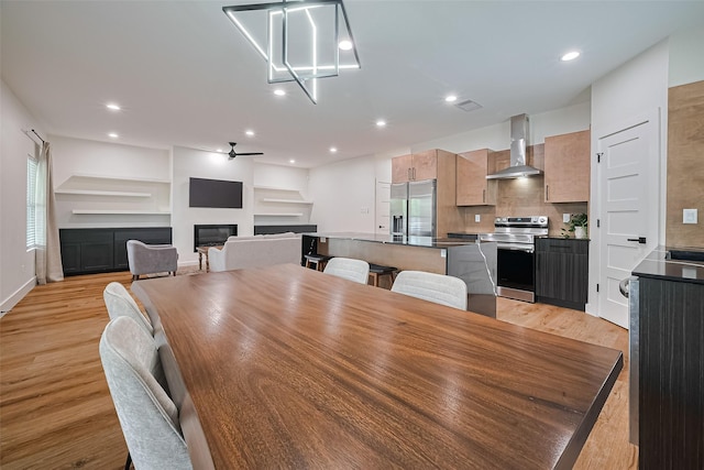 2015 Creston Dr, Houston, TX 77026 - dining room with a glass covered fireplace, light wood-style flooring, ceiling fan, and recessed lighting
