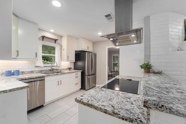 2535 Rosefield Dr, Houston, TX 77080 - kitchen featuring appliances with stainless steel finishes, island exhaust hood, tasteful backsplash, white cabinetry, and recessed lighting