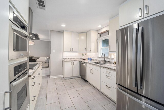 2535 Rosefield Dr, Houston, TX 77080 - kitchen with stainless steel appliances, white cabinetry, tasteful backsplash, and recessed lighting