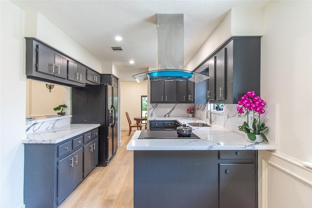 11523 Bandlon Dr, Houston, TX 77072 - kitchen featuring island exhaust hood, black appliances, a peninsula, light wood-style flooring, and recessed lighting