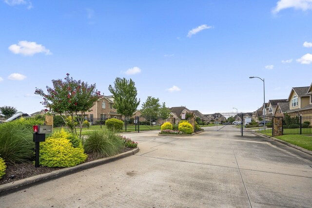 18605 Syndee Loch Ct, Spring, TX 77379 - view of concrete street featuring a residential view, a gate, curbs, and street lighting