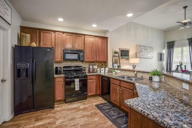 18605 Syndee Loch Ct, Spring, TX 77379 - kitchen featuring black appliances, light wood finished floors, brown cabinetry, stone countertops, and decorative backsplash