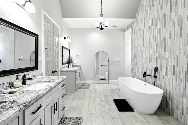 17114 Leon Ct, Splendora, TX 77372 - bathroom with tile walls, a freestanding tub, two vanities, a chandelier, and an accent wall