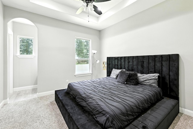 17114 Leon Ct, Splendora, TX 77372 - carpeted bedroom with arched walkways, a tray ceiling, and a ceiling fan
