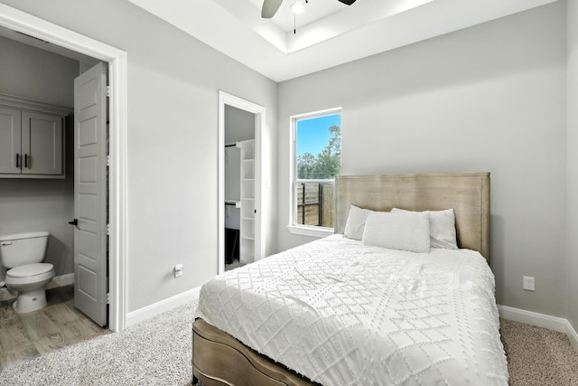 17114 Leon Ct, Splendora, TX 77372 - bedroom featuring a tray ceiling, light wood-style flooring, connected bathroom, and a ceiling fan
