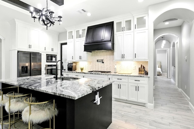 17114 Leon Ct, Splendora, TX 77372 - kitchen featuring arched walkways, appliances with stainless steel finishes, a chandelier, tasteful backsplash, and white cabinets