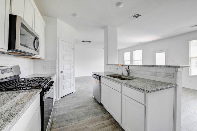 22351 Auburn Cabin Ln, Porter, TX 77365 - kitchen featuring stainless steel appliances, tasteful backsplash, light stone counters, and white cabinets