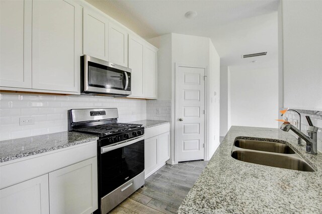 22351 Auburn Cabin Ln, Porter, TX 77365 - kitchen featuring stainless steel appliances, light wood-style floors, light stone counters, white cabinets, and tasteful backsplash