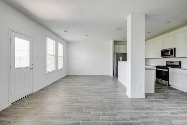 22351 Auburn Cabin Ln, Porter, TX 77365 - kitchen with stainless steel appliances, open floor plan, white cabinetry, and light wood-style flooring