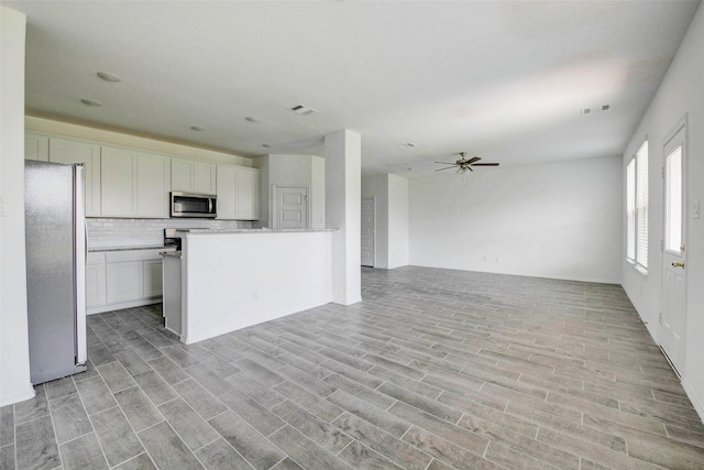 22351 Auburn Cabin Ln, Porter, TX 77365 - kitchen featuring stainless steel appliances, light wood finished floors, open floor plan, and decorative backsplash