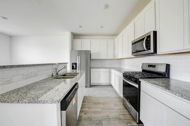 22351 Auburn Cabin Ln, Porter, TX 77365 - kitchen with stainless steel appliances, decorative backsplash, light stone counters, light wood finished floors, and white cabinetry