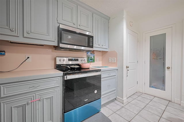 13351 Oak Leaf Ln, Houston, TX 77015 - kitchen featuring stainless steel appliances, light countertops, light tile patterned floors, and gray cabinets