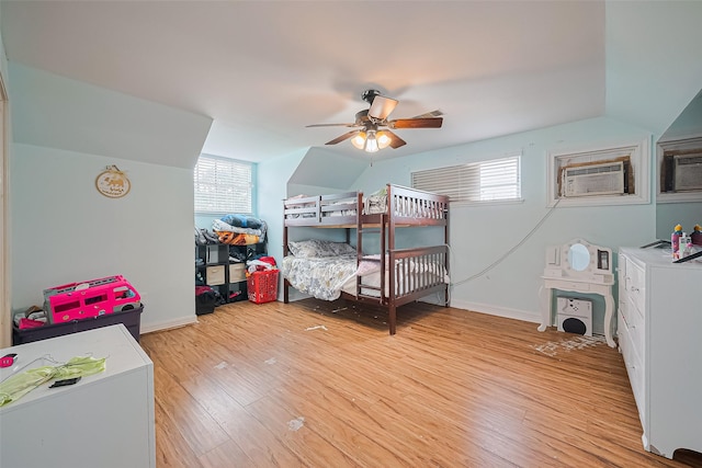 13351 Oak Leaf Ln, Houston, TX 77015 - bedroom featuring light wood-type flooring, multiple windows, vaulted ceiling, a wall unit AC, and a ceiling fan