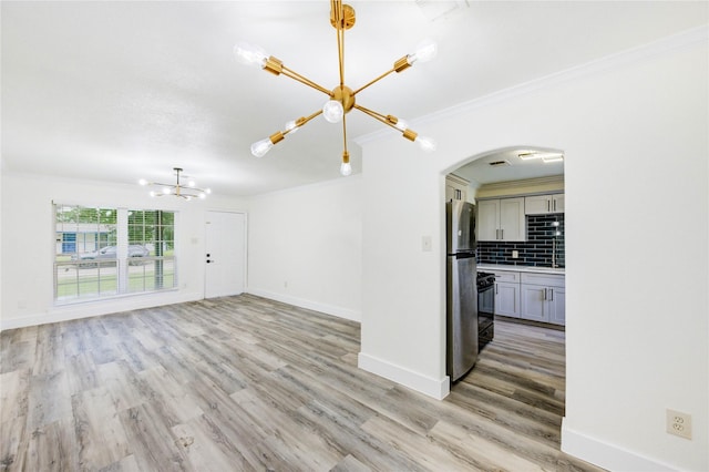 5326 Keystone St, Houston, TX 77021 - unfurnished living room featuring a chandelier, crown molding, arched walkways, and light wood finished floors